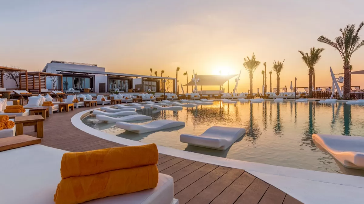 White daybeds around the pool at Nikki Beach Resort on Pearl Jumeira