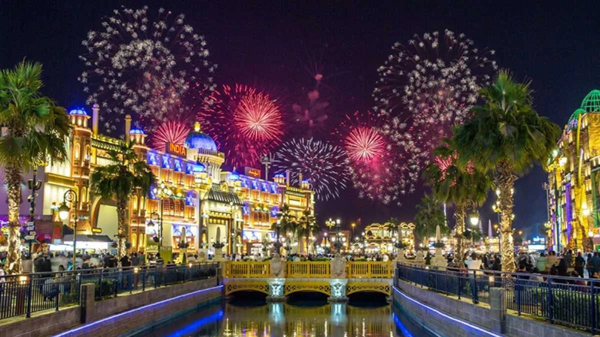 Fireworks over the Global Village canal and lit-up pavilion facades at night