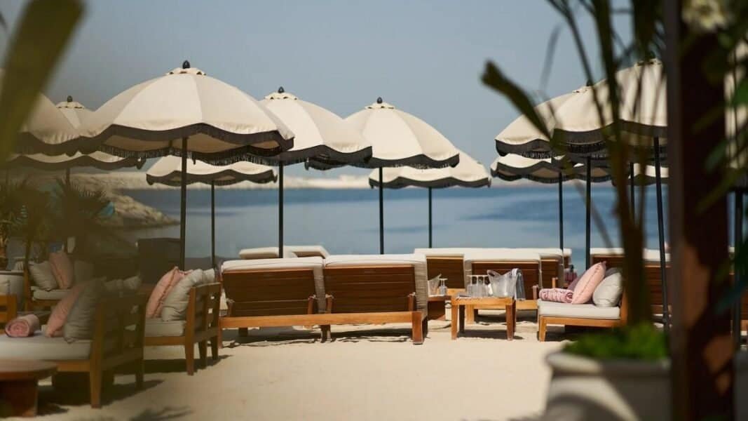 Beachside lounge at GITANO Dubai with umbrellas and seating.
