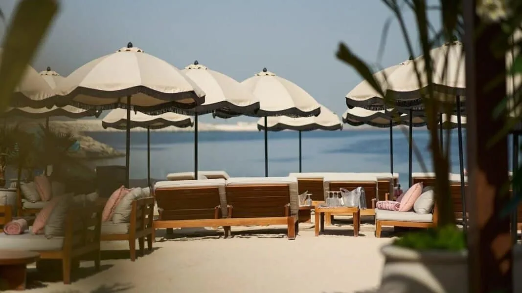 Beachside lounge at GITANO Dubai with umbrellas and seating.