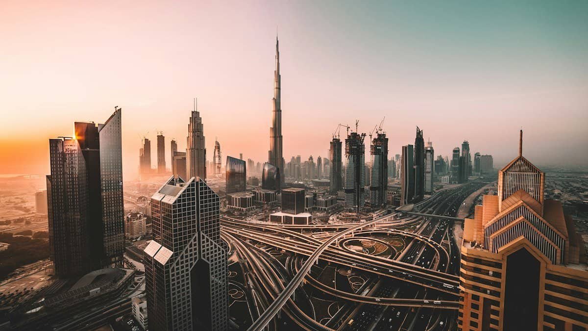 Burj Khalifa towering over the Downtown Dubai skyline and a Sheikh Zayed Road interchange at sunset