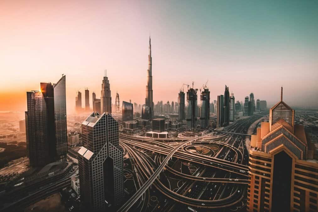 Multi-level highway interchange below the Burj Khalifa and Downtown Dubai skyline at sunrise
