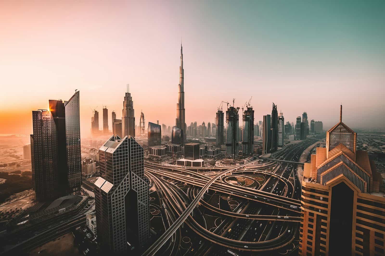 Multi-level highway interchange below the Burj Khalifa and Downtown Dubai skyline at sunrise